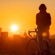 A cyclist watches the sun rise from Primrose Hill, London