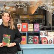 Jo Heygate, Bookshop Manager at Pages of Hackney holds up the book Antiemetic for Homesickness by Romalyn Ante.