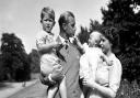 A photo dated August, 9, 1951, of the Princess Royal in the arms of Queen Elizabeth II, with The Duke of Edinburgh, holding The Prince of Wales, in the grounds of Clarence House.